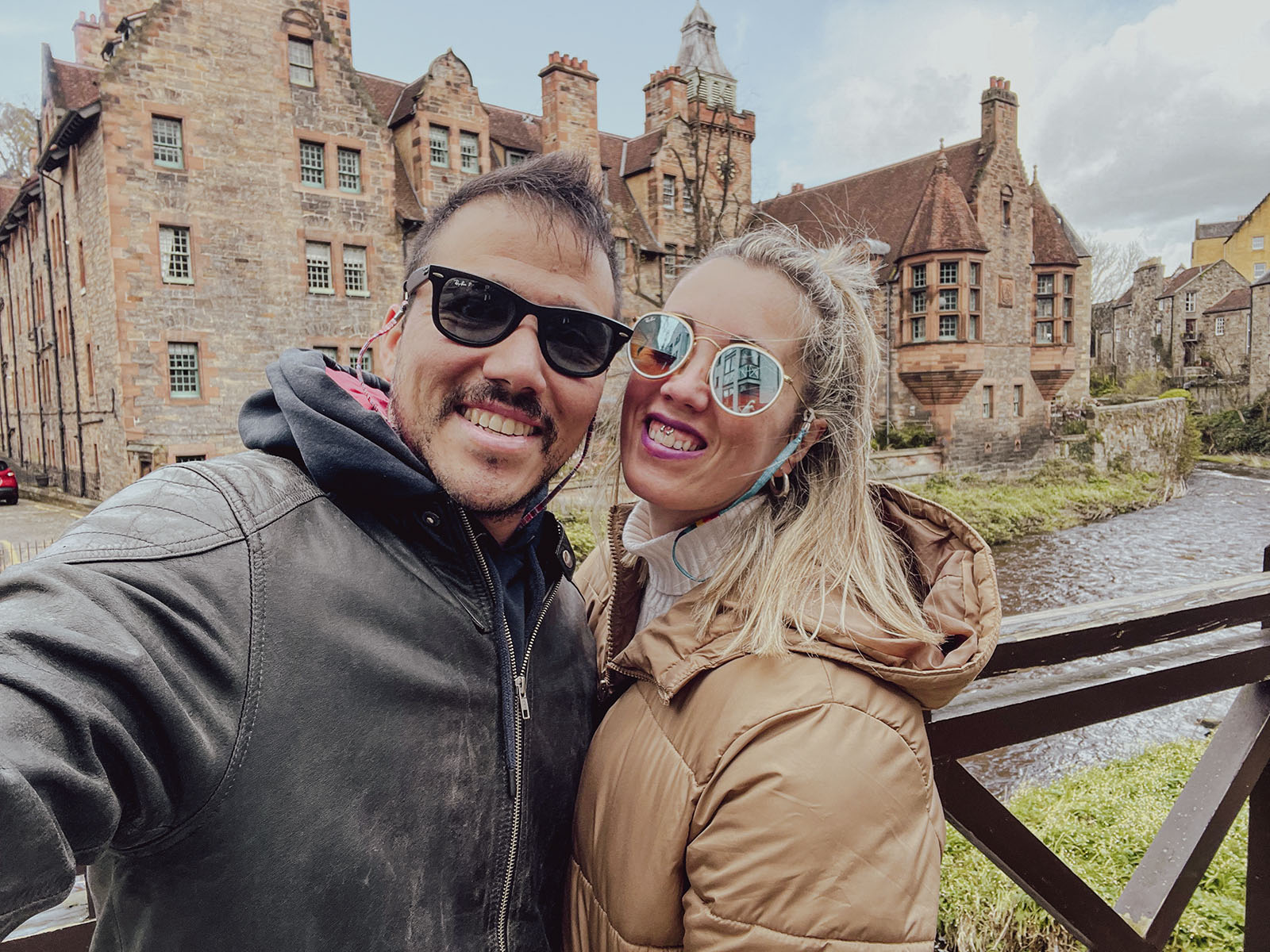 Hugo y Celia sonriendo junto a un río y edificios de piedra